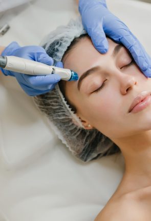 View from above rejuvenation of beautiful woman enjoying cosmetology procedures in beauty salon. Dermatology, hands in blue glows, healthcare, therapy, botox